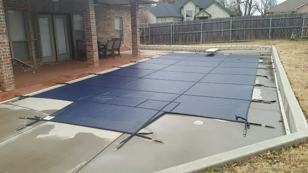 Navy safety cover closed over an inground pool for an Oklahoma winter
